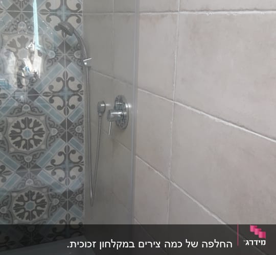 מקלחת עם אריחים מעוצבים וראש מקלחת כסוף